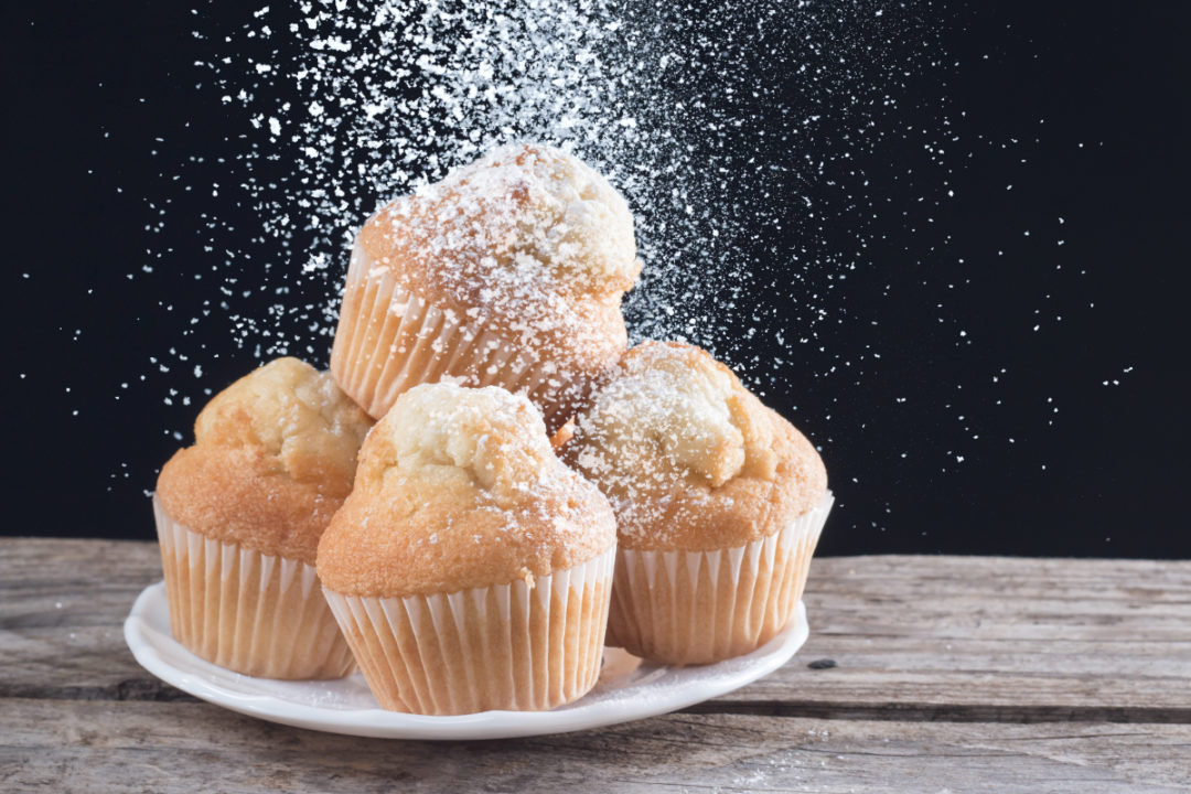 Sugar pouring onto muffins