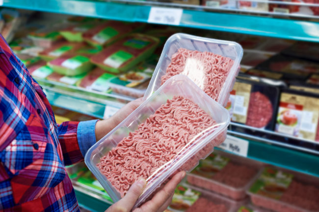 Grocery shopper choosing between two ground meat options