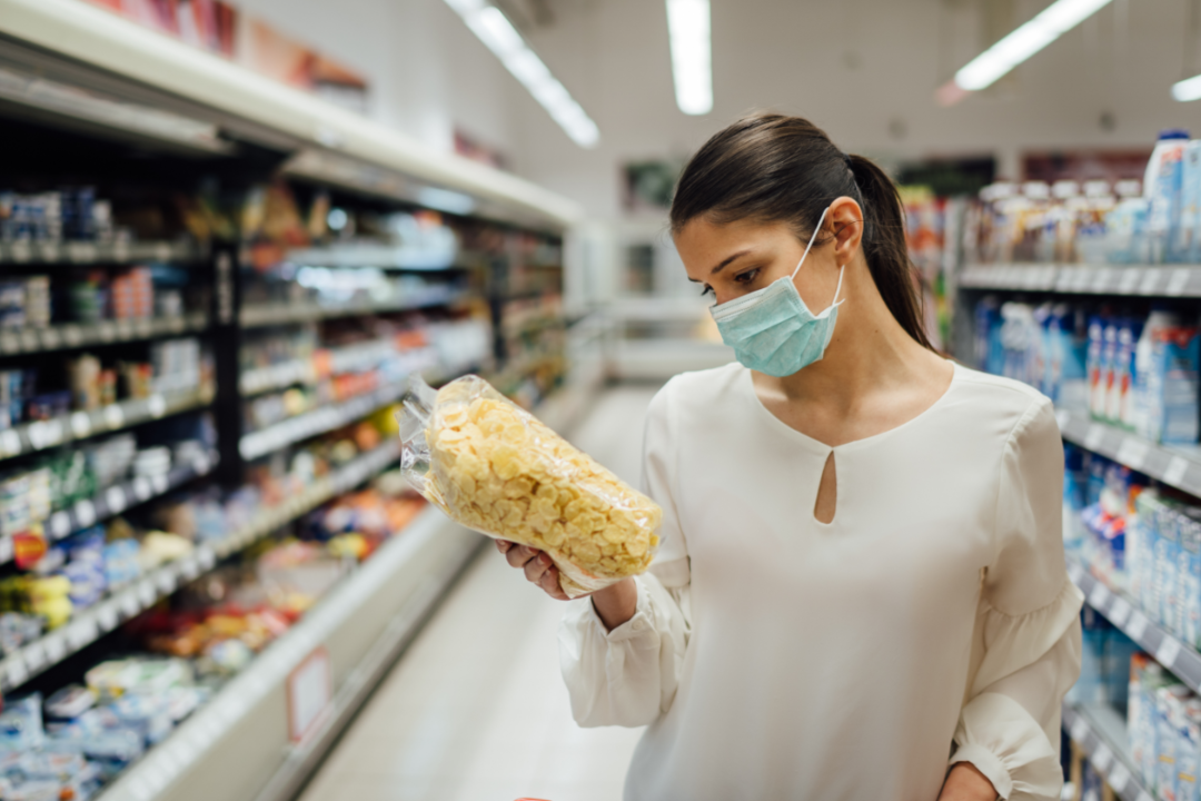 Woman grocery shopping while wearing a protective face mask