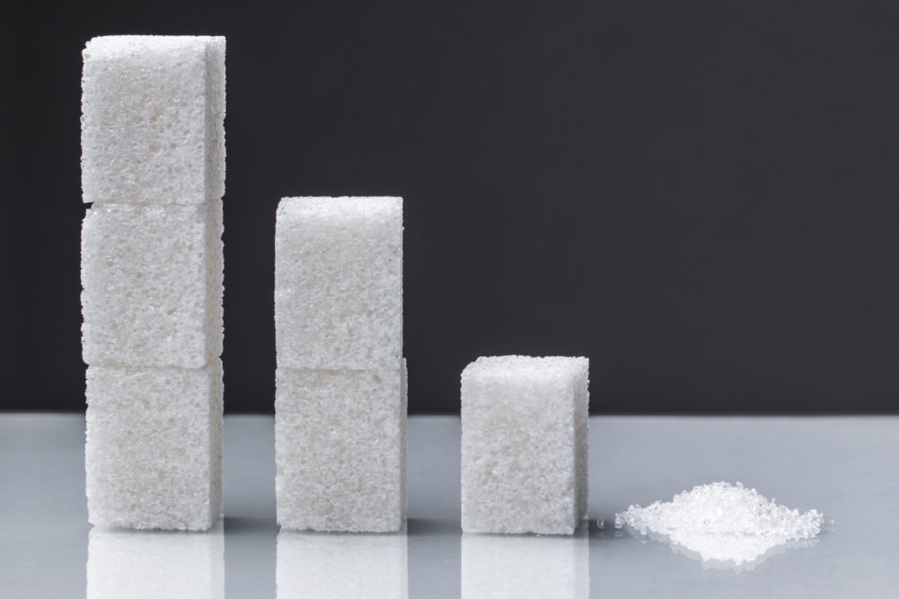 Stacks of sugar cubes descending into a small pile of sugar - sugar reduction concept