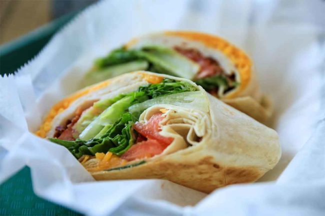 Photo of a turkey wrap with lettuce and tomatoes served in a basket
