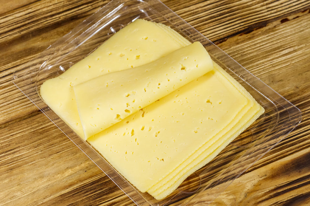 slices-of-cheese-in-plastic-container-on-wooden-surface