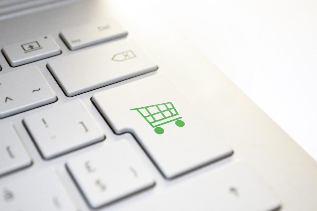 Close-up of keys on white keyboard with a key that has a green shopping cart icon