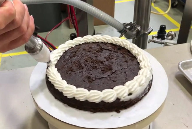 machine decorating a chocolate cake
