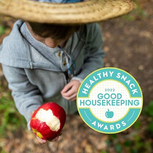 person with a straw hat holding a pink lady apple with a bite taken out