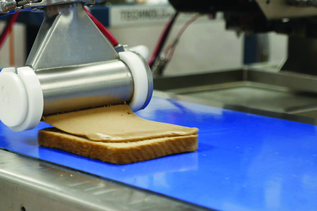 unifiller equipment deposits peanut butter on slice of bread