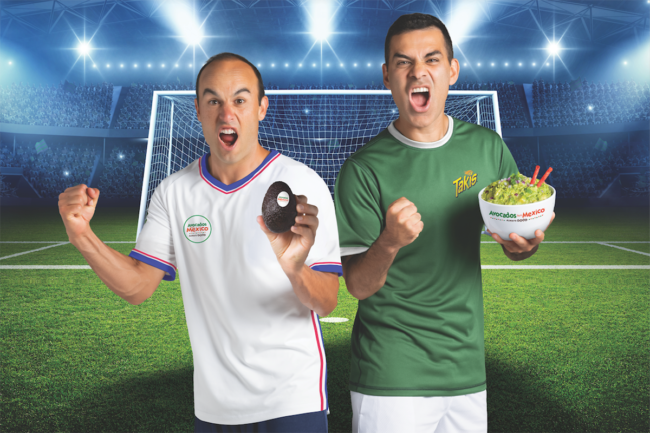 two soccer players holding AFM avocados and a bowl of guacamole with Takis on a soccer field
