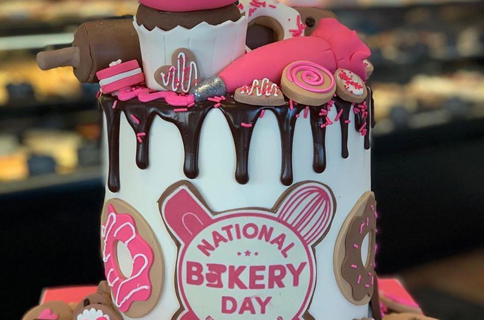pink and white cake that says "national bakery day"