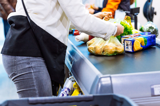 person putting groceries on belt for checkout