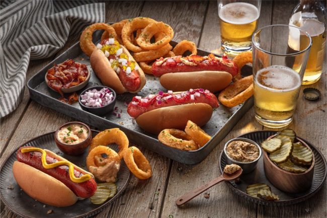 spread of hot dogs on plates on a wooden table