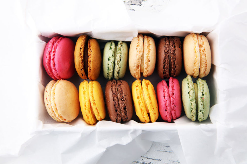 Variety of macarons in a white box with tissue paper