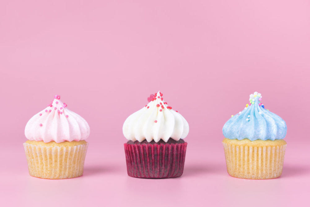 three small cupcakes on a pink background