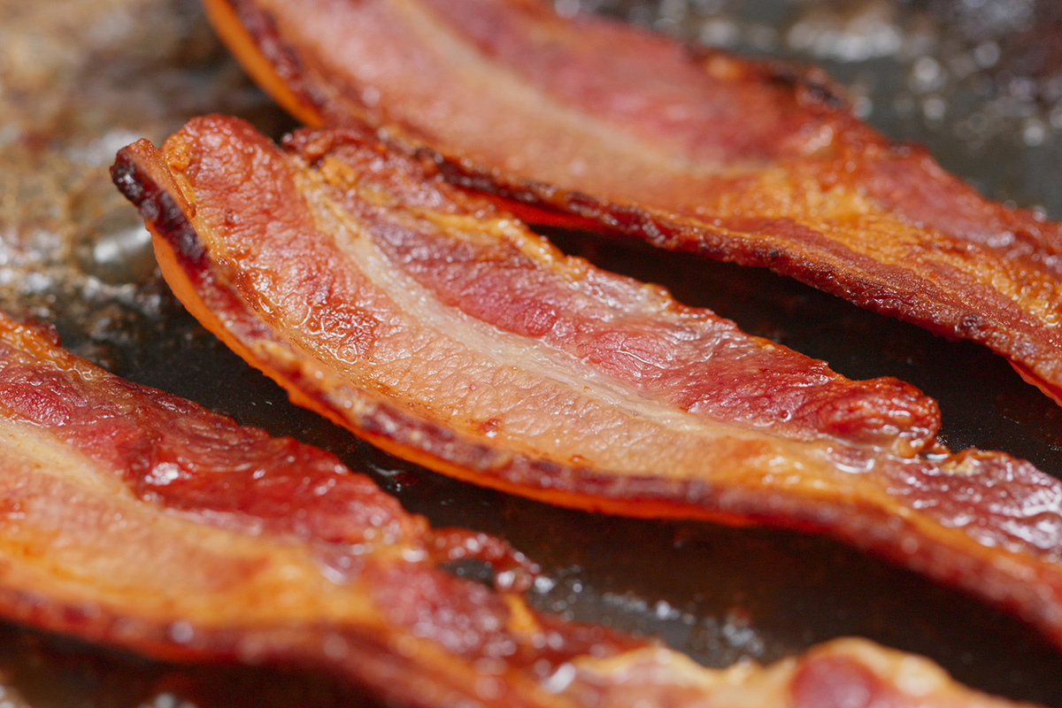 strips of bacon frying on a pan