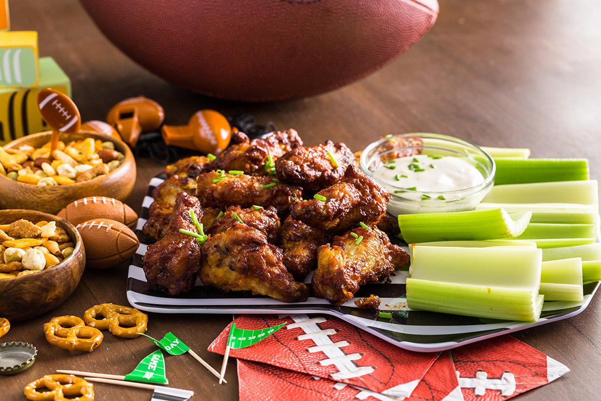 Chicken wings and celery on a plate on a table with football-themed party decorations