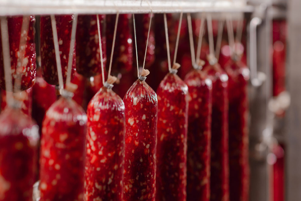 Salami production. Sausage production line. Sausage on the counter for the smokehouse. Meat processing plant