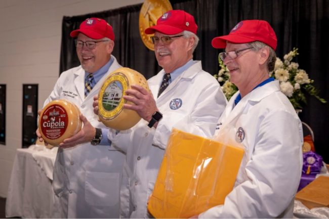 Three people at US Championship Cheese Contest holding cheese