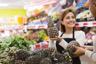 woman in a grocery store holding a pineapple
