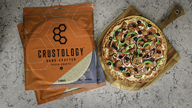 Baker's Quality Crustology pizza crust in packaging next to a cooked pizza