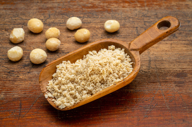macadamia nut flour in wooden scoop on a rustic weathered wood, gluten-free starch substitute
