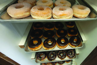 donuts on pans on shelves
