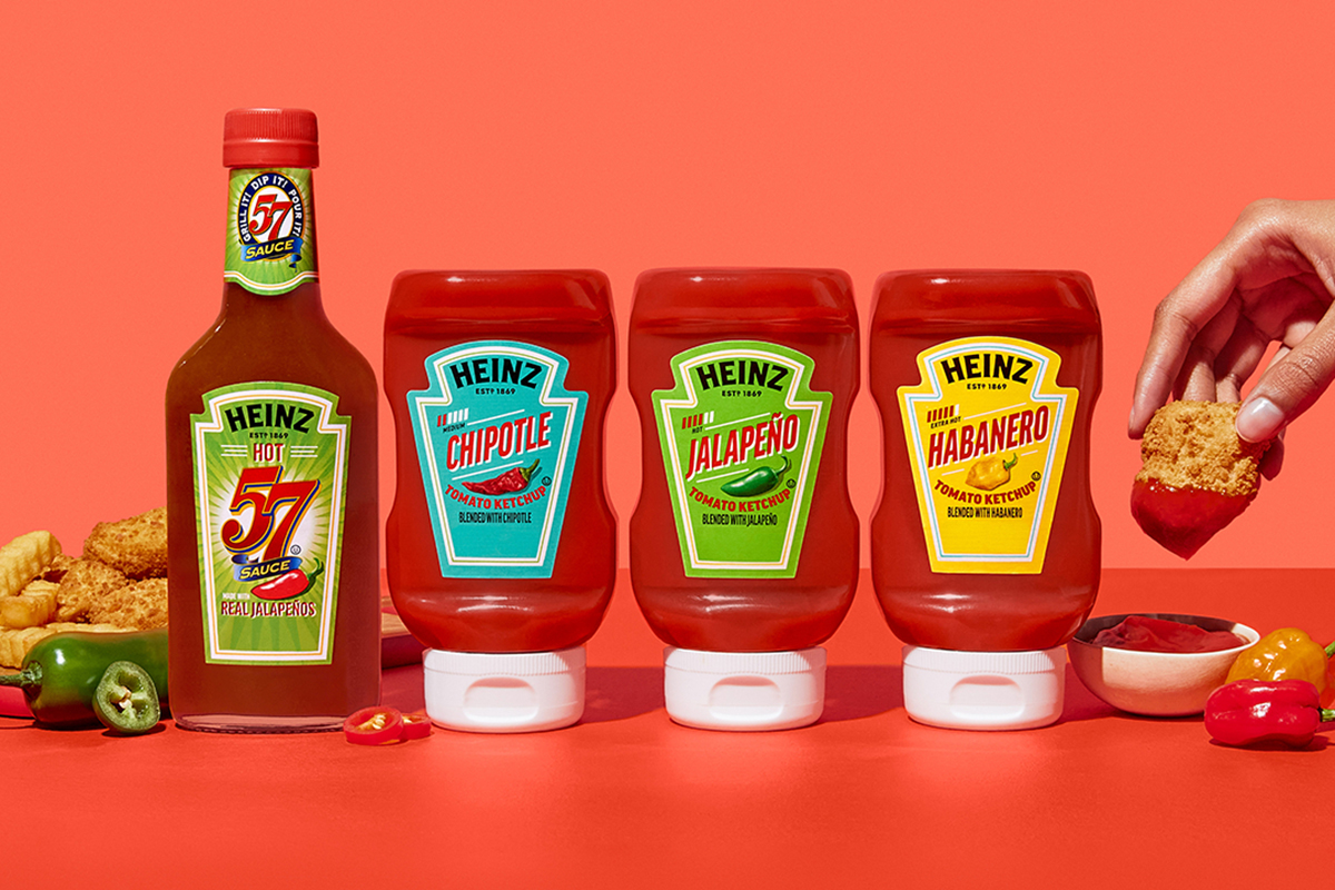 Heinz ketchup and hot sauce bottles lined up on a red background