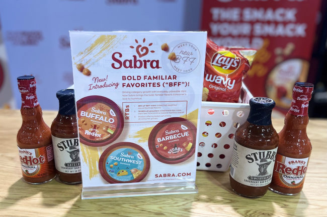 Stubb's barbecue sauce and Frank's RedHot sauce net to a sign showing three new hummus flavors