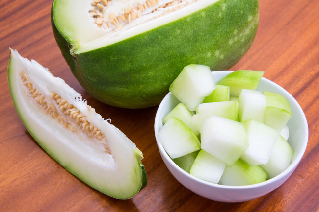 Fresh cut winter melon in a bowl on a wooden surface