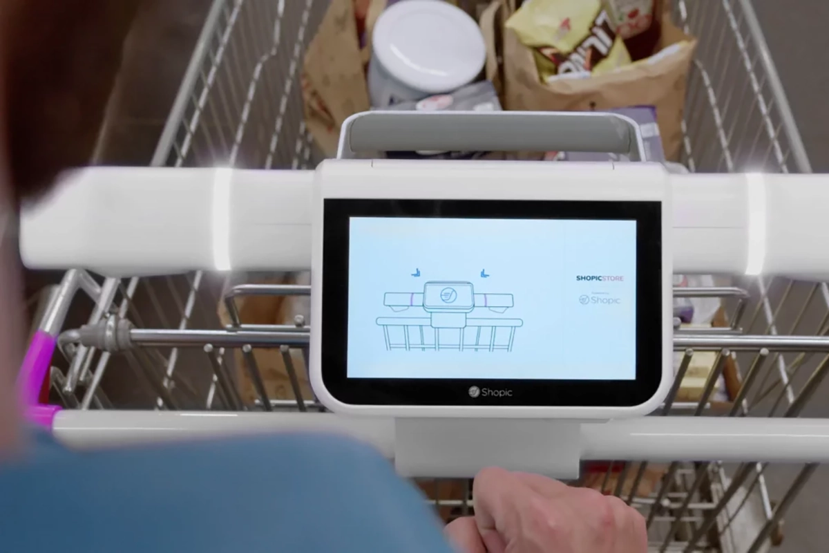 shopic tablet on a grocery cart with someone's hand pushing the cart