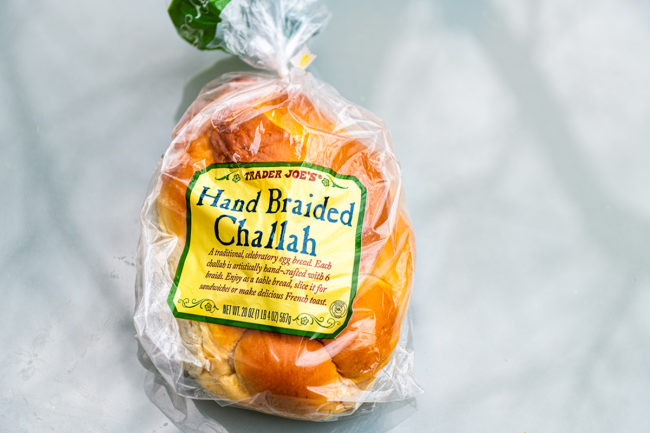 Large loaf of yellow Challah packaged in plastic storebought at Trader Joe's and sign for hand braided bread