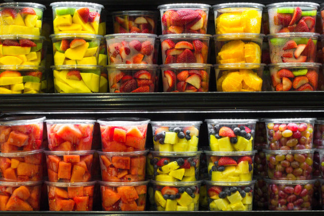 fresh-cut fruits in plastic packages on shelves