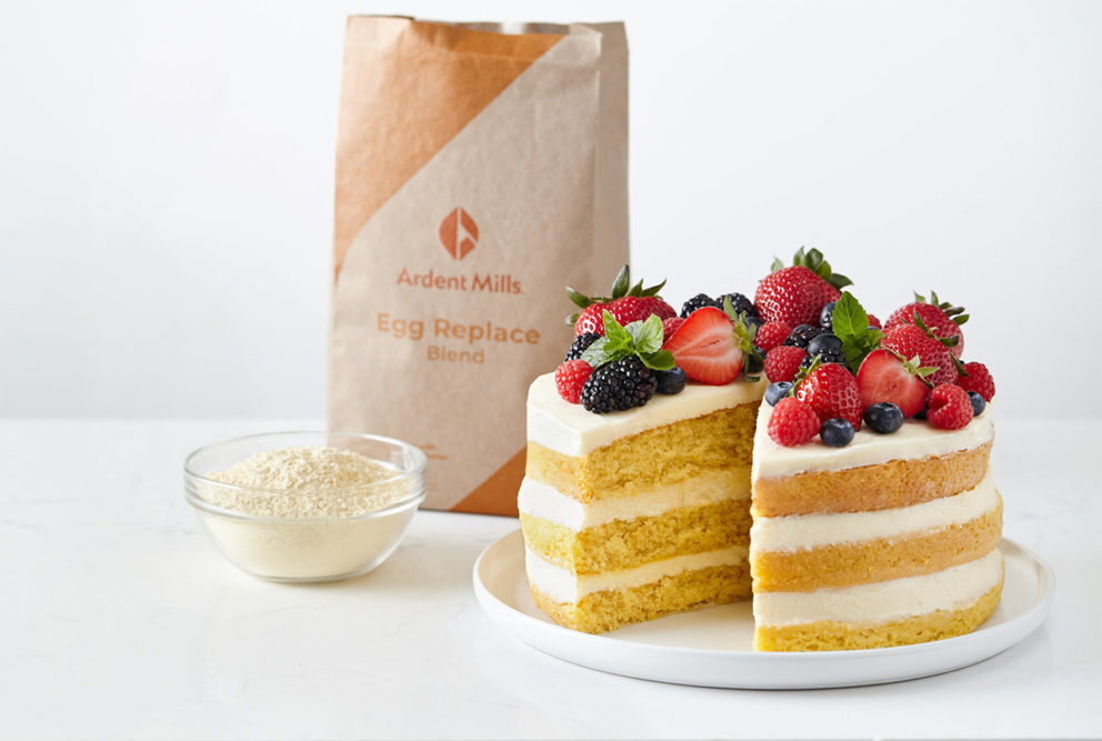 cake with berries on top next to Ardent Mills Egg Replace bag