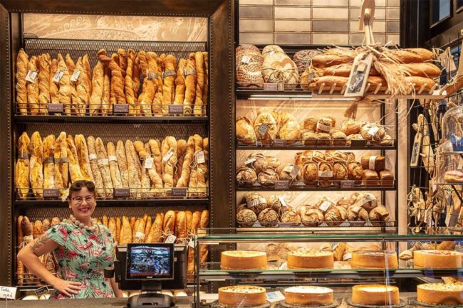 stacks of bread with a woman smiling in front of them