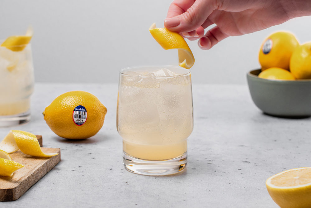 cocktail with lemon being squeezed over it
