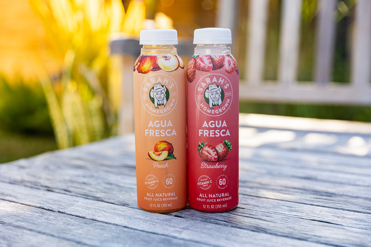 two juice bottles on a wooden table outside