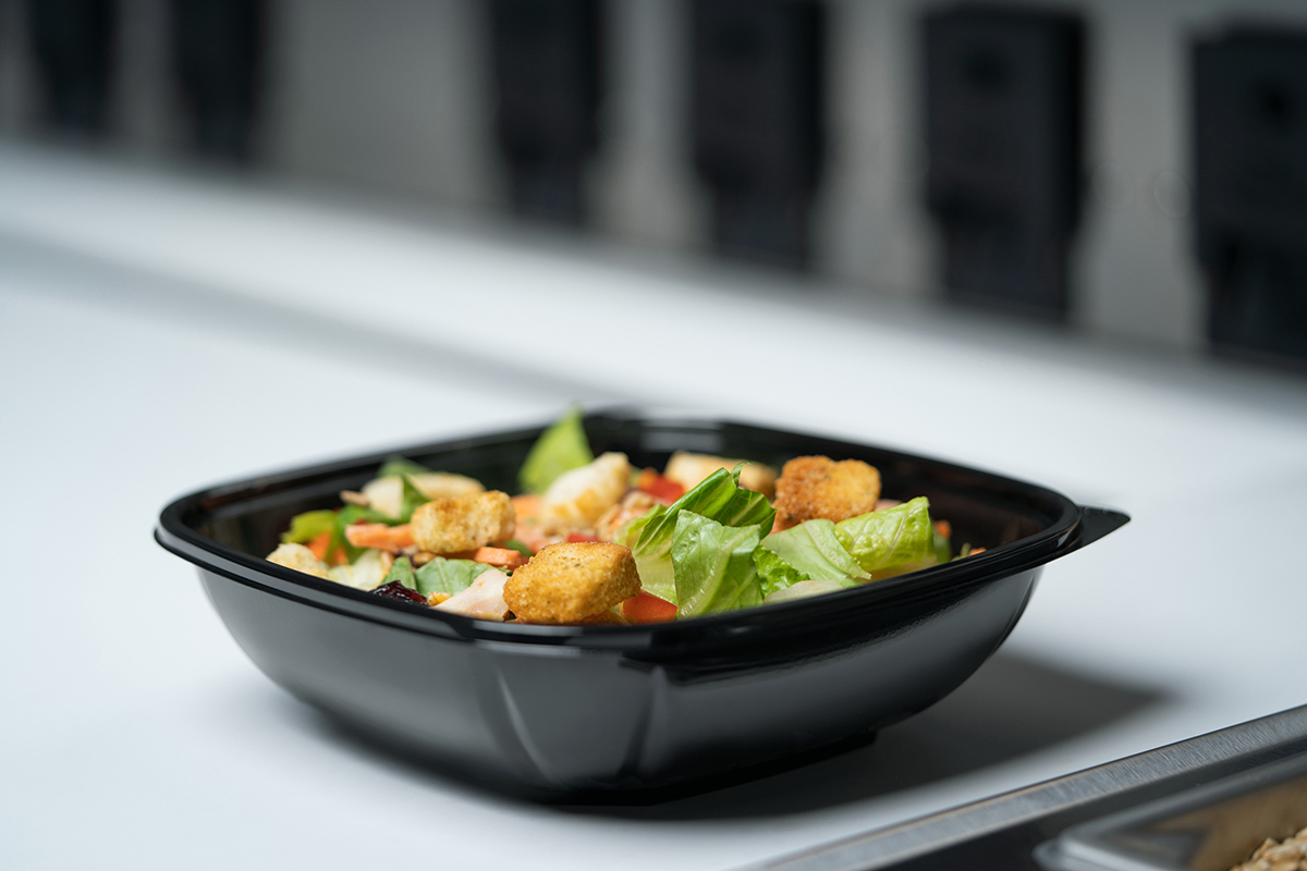 open, plastic, black to-go container with salad