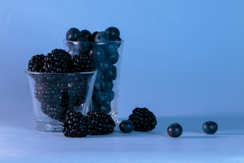 Still life of a blueberries and blackberries against blue background