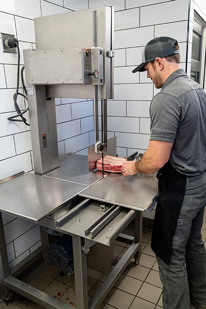 standing person operating a meat saw
