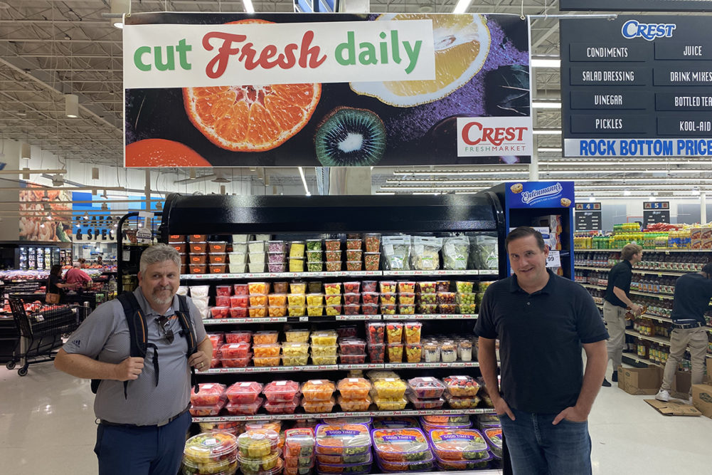 two men standing in produce department in a supermarket