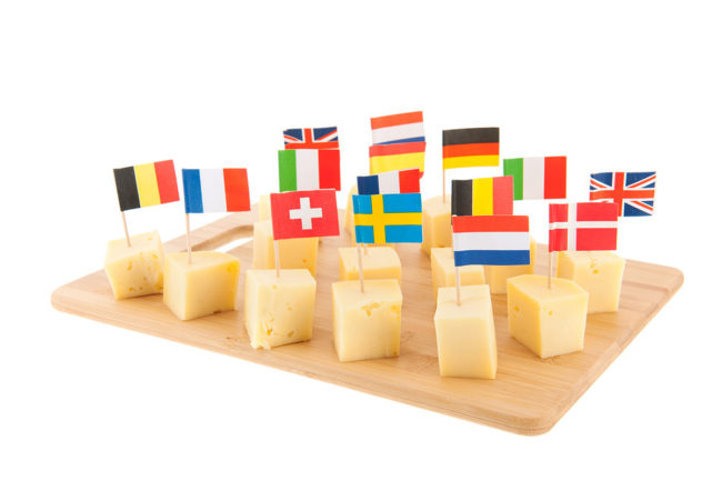 cubes of cheese with flags from various countries on toothpicks in the cheese