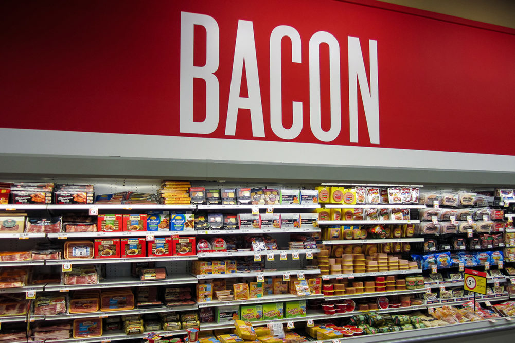 grocery store shelves with bacon sign overhead