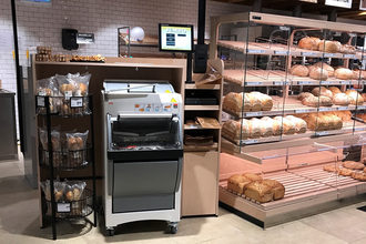 automated slicer next to shelves of bread