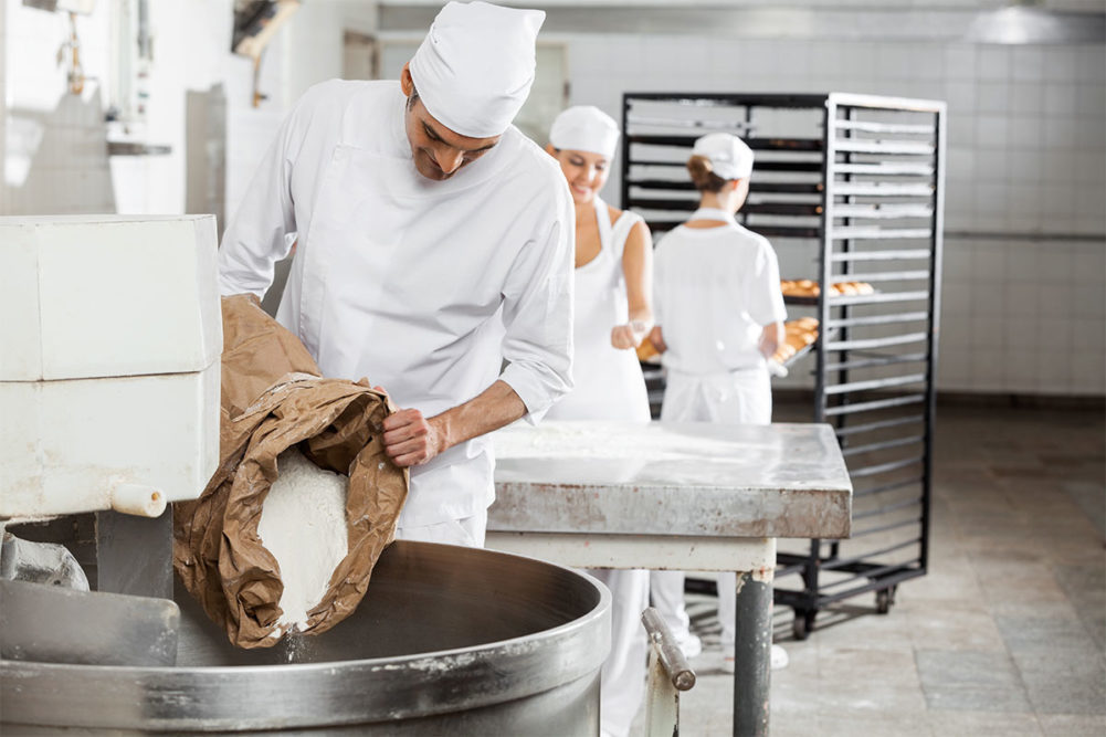 bakers in a facility adding ingredients to a mix