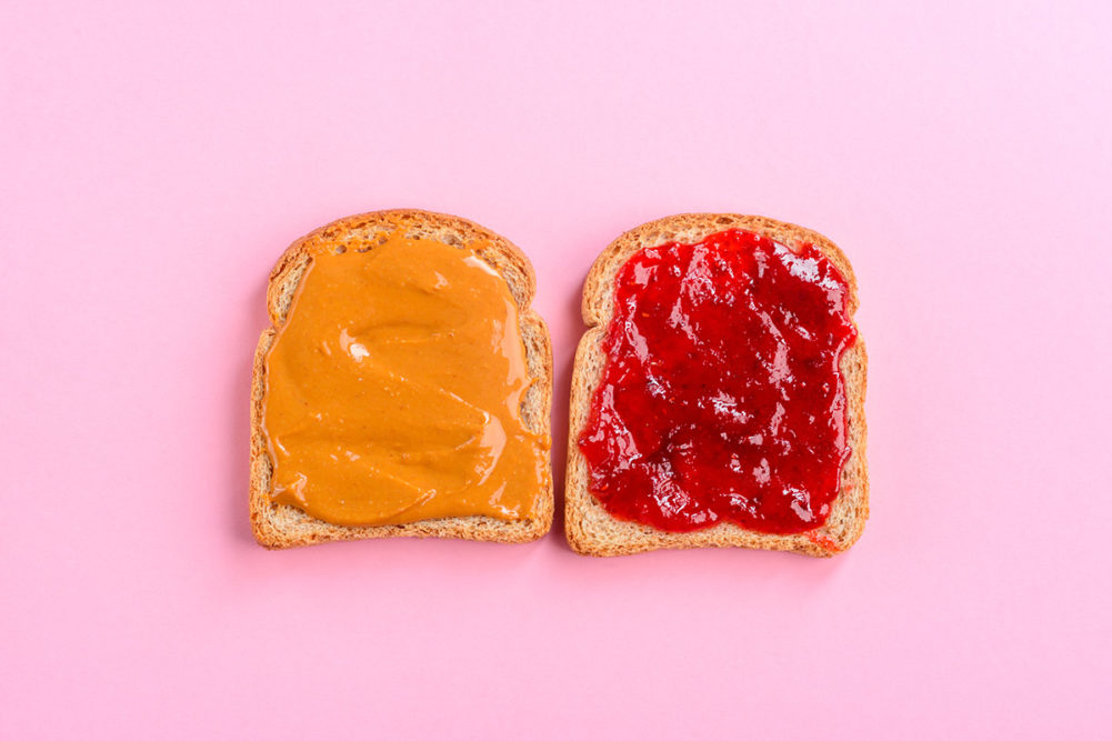 open peanut butter and jelly sandwich on pink background
