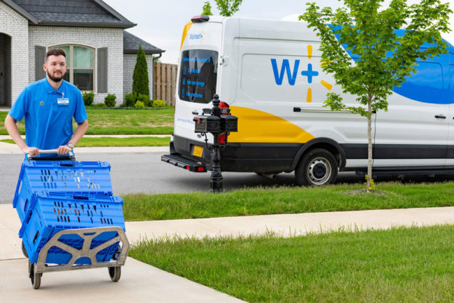 walmart employee wheeling delivery crates up a suburban driveway 