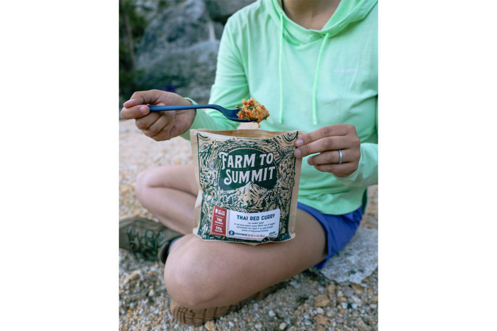 hiker eating plant-based meal out of Farm to Summit package