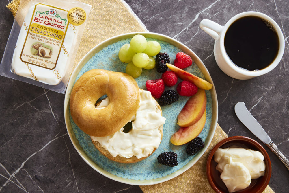 creamy cheese spread on a bagel on a plate with fruit