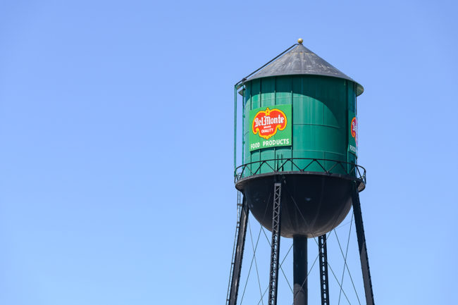 Yakima, WA, USA - July 11, 2022; Traditional green water tower with sign for Del Monte Band Quality Food Products against a blue sky