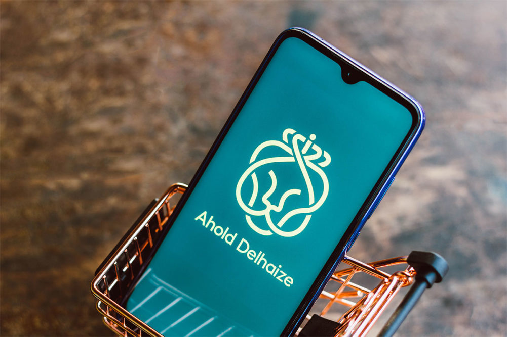 Ahold-Delhaize-Logo-on a smart phone in a mini grocery basket