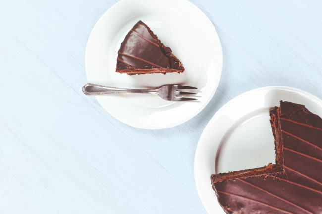 slice of chocolate cake on a white plate sitting on a blue background